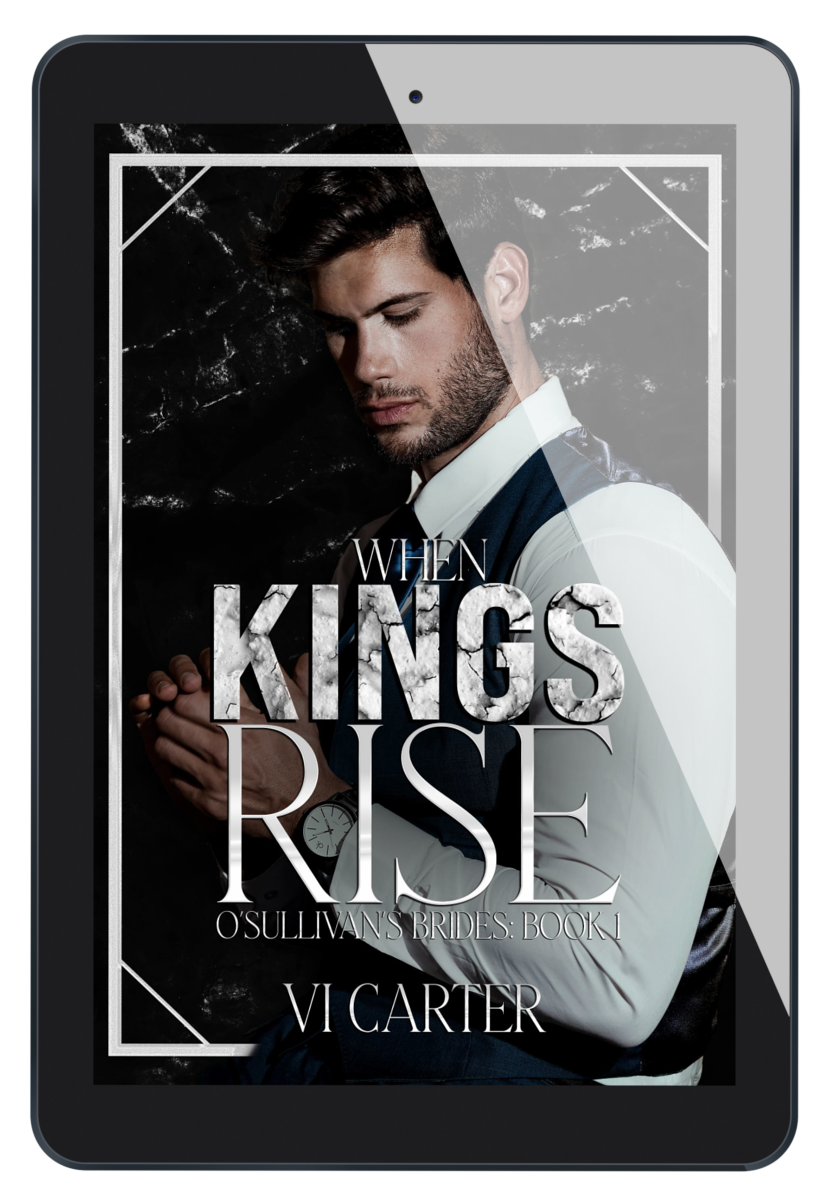 This image features the cover of the book "When Kings Rise" by Vi Carter, displayed on a tablet. The book cover shows a intense and brooding man with a dark suit and a shadowed face, adding a sense of mystery and tension.